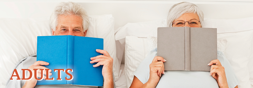 Two older adults reading books in bed